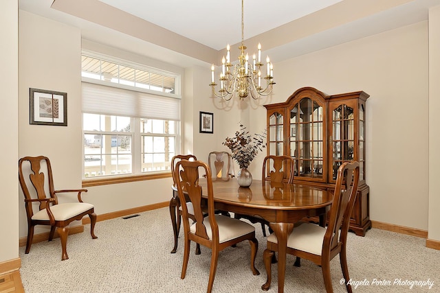 dining room featuring light colored carpet and a chandelier