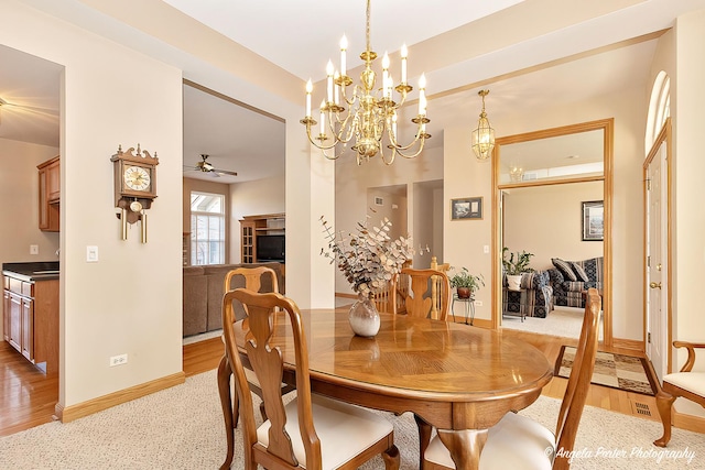 dining space featuring ceiling fan with notable chandelier