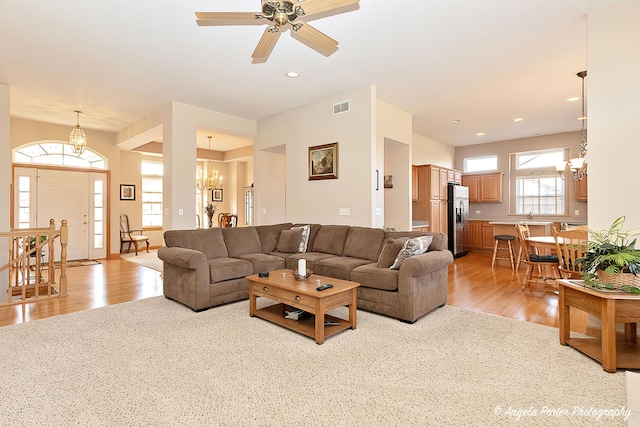 living room with light colored carpet and ceiling fan with notable chandelier