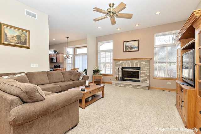 living room with a fireplace, light carpet, and ceiling fan with notable chandelier