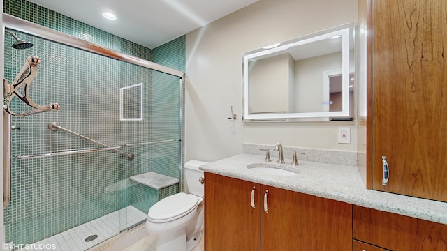 bathroom with vanity, toilet, and a shower with door