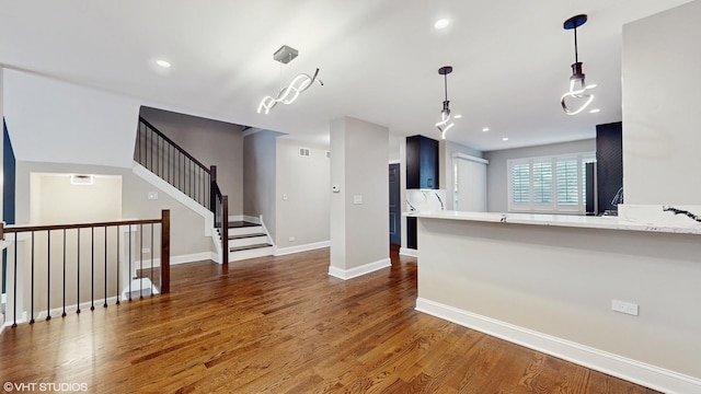 kitchen featuring kitchen peninsula, dark hardwood / wood-style flooring, and hanging light fixtures