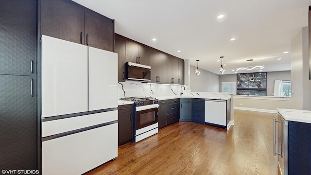 kitchen with sink, hanging light fixtures, dark hardwood / wood-style floors, kitchen peninsula, and white appliances