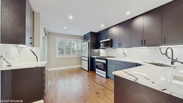 kitchen with decorative backsplash, light stone counters, sink, and range with gas stovetop