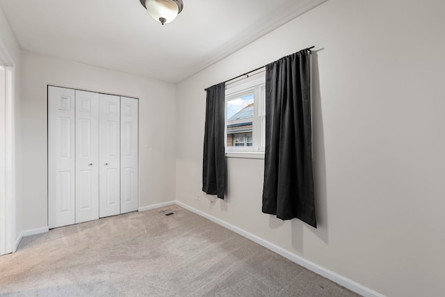 unfurnished bedroom with light carpet and a closet