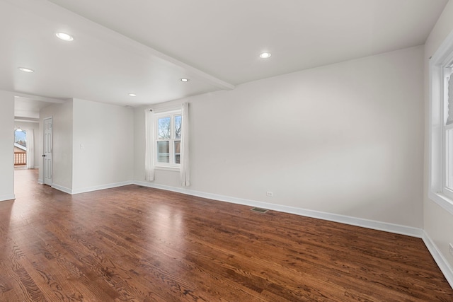 empty room with beam ceiling and dark hardwood / wood-style flooring