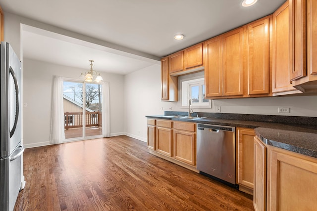 kitchen featuring sink, dark wood-type flooring, hanging light fixtures, an inviting chandelier, and appliances with stainless steel finishes