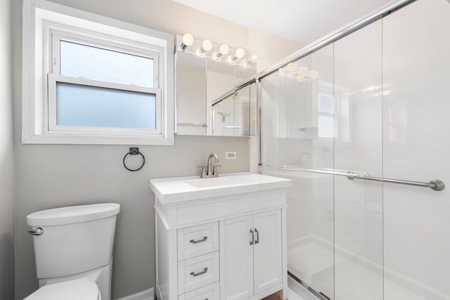 bathroom with a shower with door, vanity, and toilet