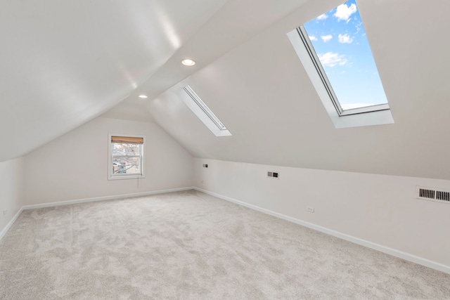 additional living space with light carpet, plenty of natural light, and vaulted ceiling with skylight