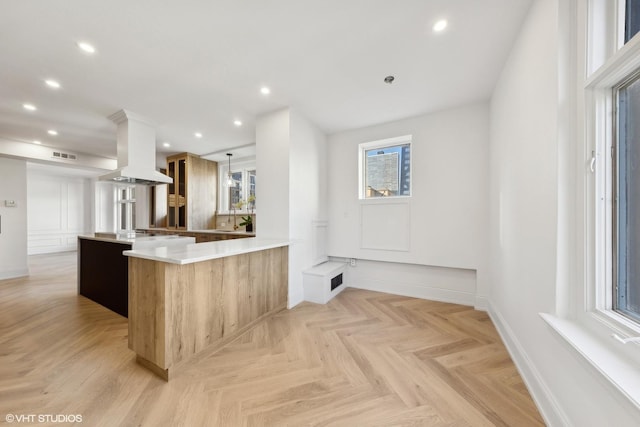 kitchen with kitchen peninsula, island exhaust hood, and light parquet flooring