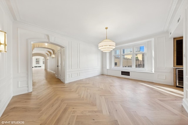 unfurnished living room with ornamental molding, wine cooler, and light parquet flooring