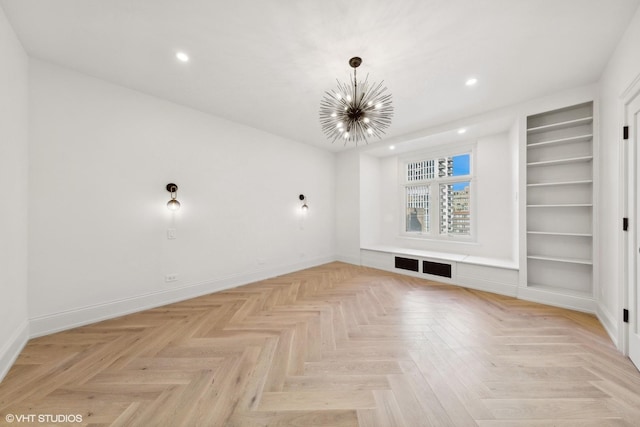 empty room with built in features, light parquet floors, and a notable chandelier