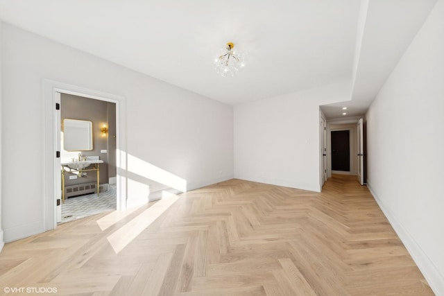 spare room with an inviting chandelier and light parquet floors