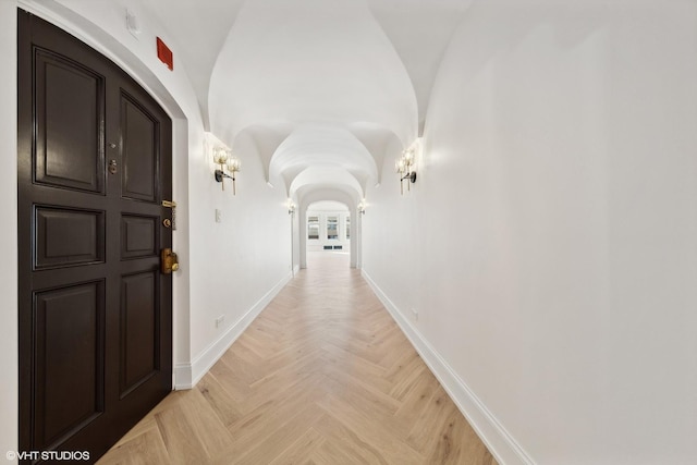 hallway featuring light parquet flooring and vaulted ceiling