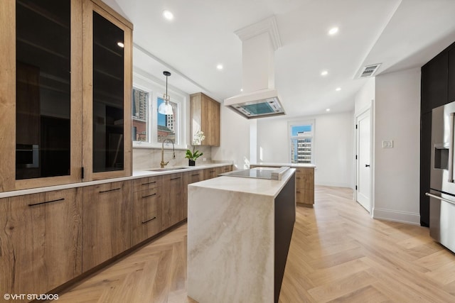 kitchen featuring pendant lighting, sink, black electric cooktop, a kitchen island, and light parquet flooring