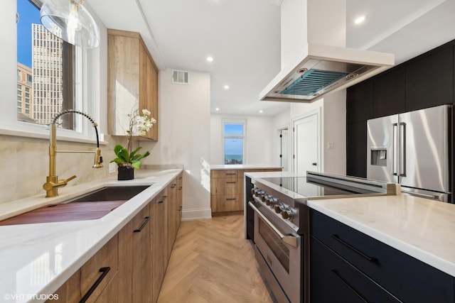 kitchen with pendant lighting, high end appliances, light parquet floors, sink, and island exhaust hood