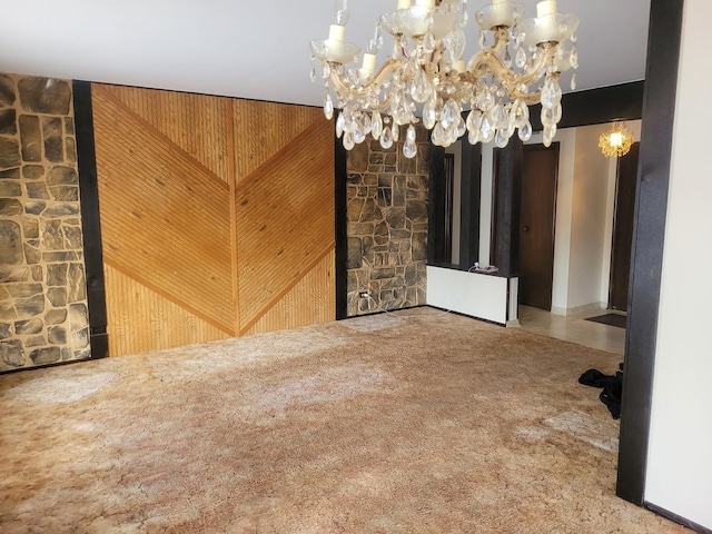 carpeted empty room featuring wood walls and a chandelier