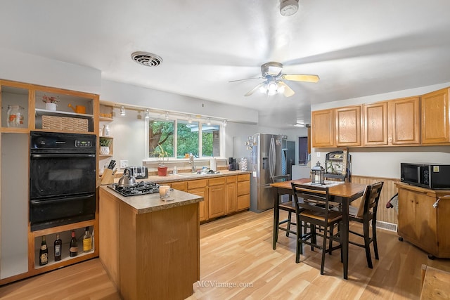 kitchen with light wood-type flooring, kitchen peninsula, sink, and stainless steel appliances