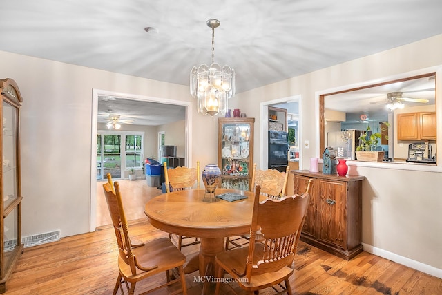 dining area featuring ceiling fan with notable chandelier and light wood-type flooring