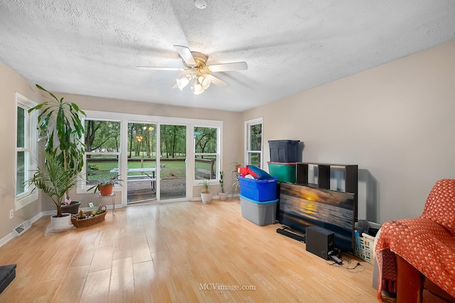 interior space featuring ceiling fan, light hardwood / wood-style floors, and a textured ceiling