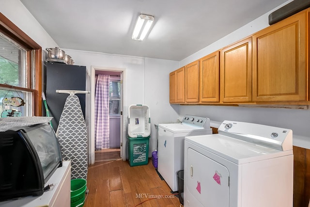 laundry room with dark hardwood / wood-style floors, cabinets, and separate washer and dryer