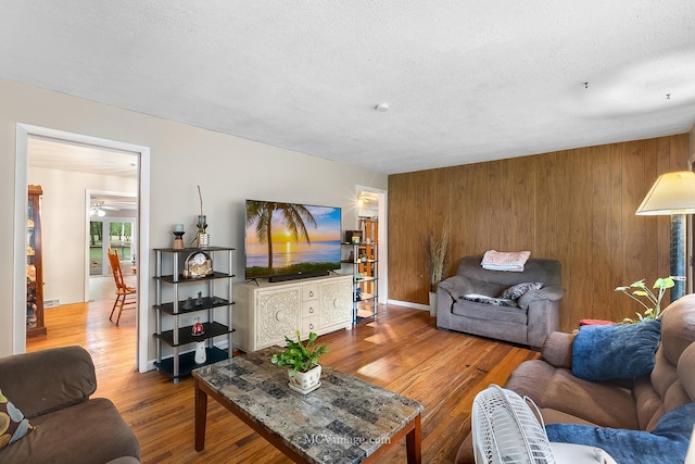 living room featuring hardwood / wood-style floors, a textured ceiling, and wooden walls