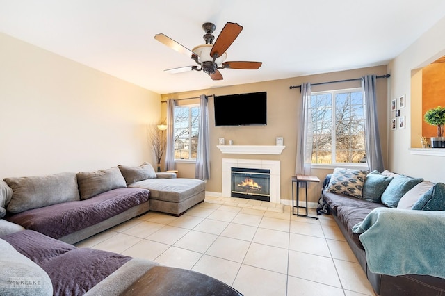 living room with light tile patterned floors, a tiled fireplace, a ceiling fan, and a wealth of natural light