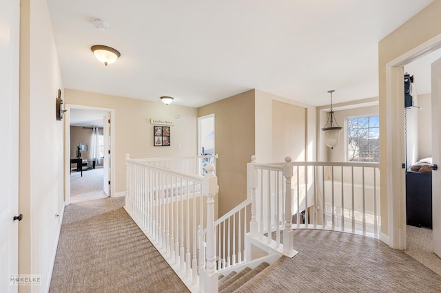 hall with baseboards, an upstairs landing, and carpet