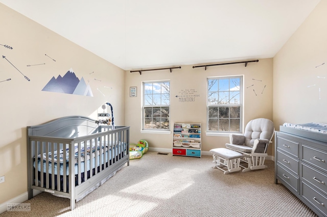 carpeted bedroom featuring baseboards and a nursery area