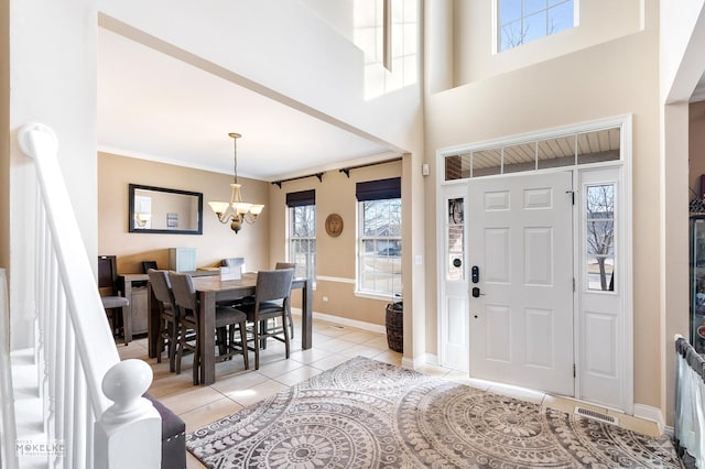 entrance foyer featuring light tile patterned floors, plenty of natural light, a chandelier, and baseboards