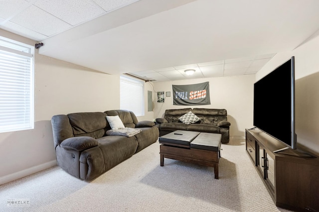 living area featuring light carpet, a drop ceiling, and baseboards