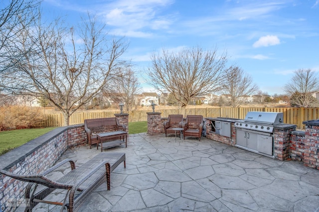 view of patio / terrace with an outdoor kitchen, a grill, a fenced backyard, and outdoor lounge area