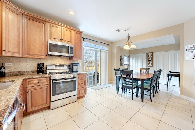 kitchen featuring light tile patterned floors, light stone countertops, tasteful backsplash, and appliances with stainless steel finishes