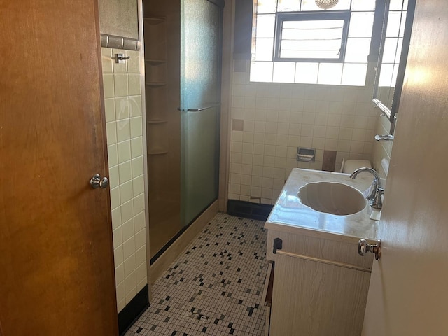 bathroom with tile patterned floors, vanity, an enclosed shower, and tile walls