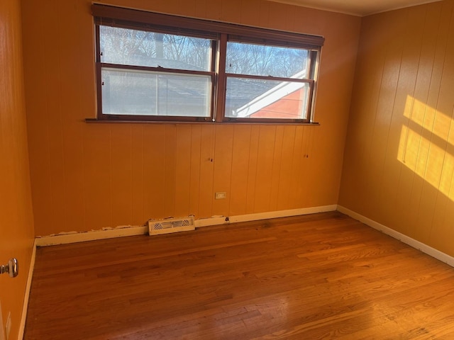 spare room featuring wooden walls and light hardwood / wood-style flooring