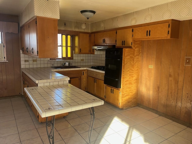 kitchen featuring tile counters, sink, gas stovetop, oven, and light tile patterned floors