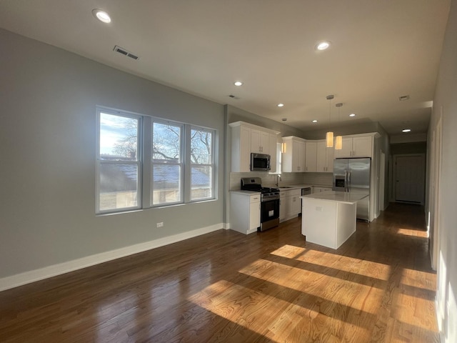 kitchen with a center island, hanging light fixtures, stainless steel appliances, dark hardwood / wood-style floors, and white cabinets