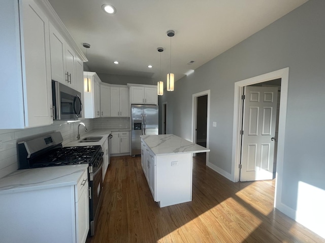 kitchen featuring pendant lighting, stainless steel appliances, a kitchen island, and white cabinetry