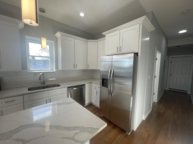 kitchen with pendant lighting, white cabinets, sink, light stone counters, and stainless steel appliances