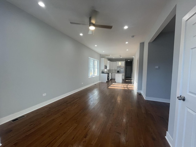 unfurnished living room featuring ceiling fan and dark wood-type flooring