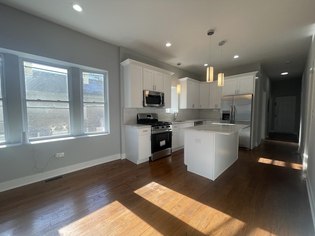 kitchen featuring appliances with stainless steel finishes, sink, pendant lighting, white cabinets, and a kitchen island