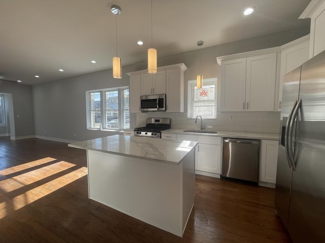 kitchen with stainless steel appliances, white cabinetry, a kitchen island, and sink