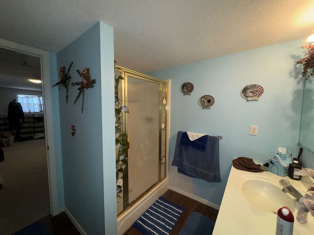 bathroom featuring hardwood / wood-style flooring, vanity, walk in shower, and a textured ceiling