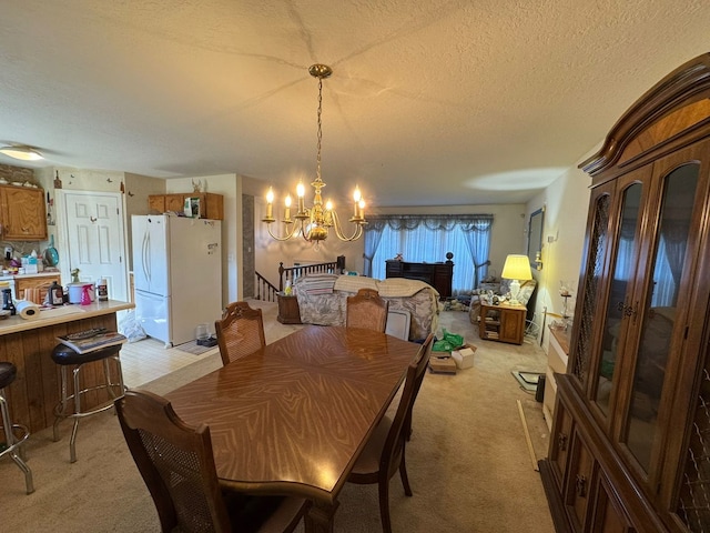 dining room featuring light colored carpet, a chandelier, and a textured ceiling