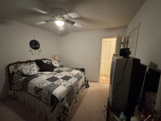 bedroom featuring a textured ceiling, light colored carpet, and ceiling fan