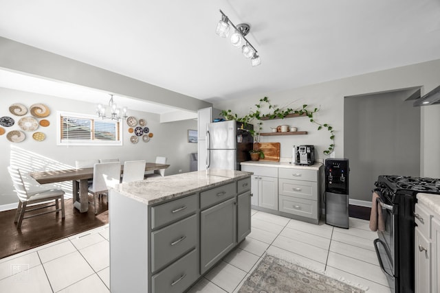 kitchen with stainless steel refrigerator, decorative light fixtures, a center island, light tile patterned floors, and gas stove