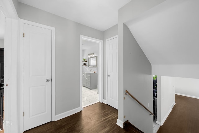 corridor with dark hardwood / wood-style flooring, sink, and vaulted ceiling