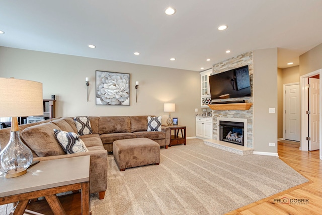 living room featuring light wood-type flooring and a stone fireplace