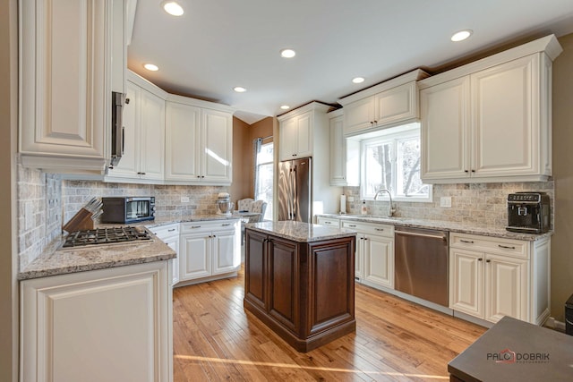 kitchen with white cabinets, stainless steel appliances, light stone counters, and a kitchen island