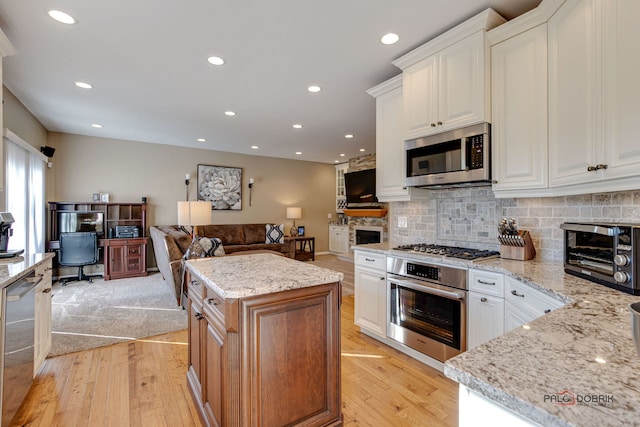 kitchen featuring stainless steel appliances, a kitchen island, white cabinets, and light stone countertops